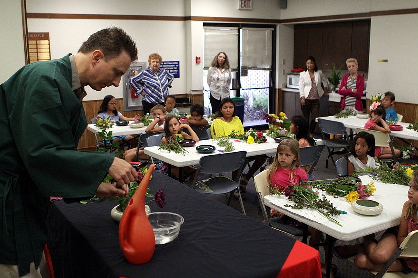 Sensei Gil Lee shows the students how to properly place the plants and flowers in their arrangements, Thursday, May 12, at Gulf Gate Library.