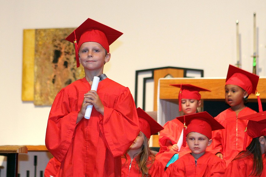 Michael Fesko, 5, stands with his diploma as his parents and others take photos.