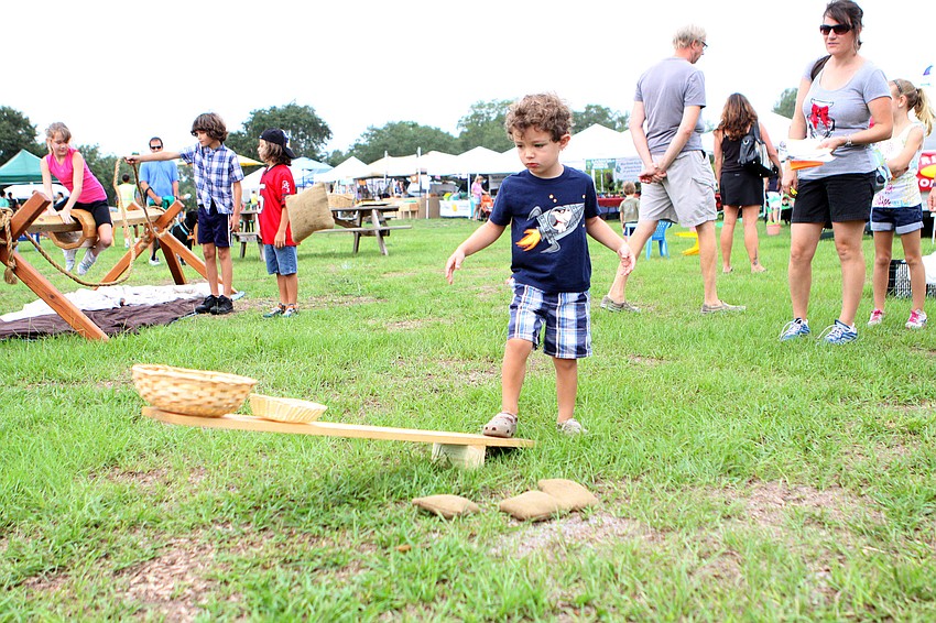 Jake Croft, 3, stomps on a wooden board in order to get a beanbag to fly up in the air.
