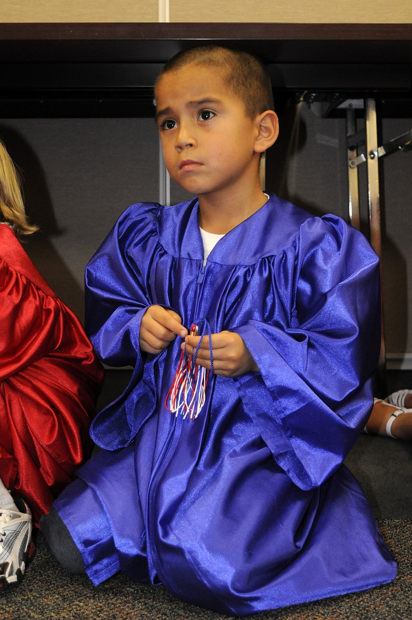 Adrian Elorreaga, 5, attempts to fix his tassel.
