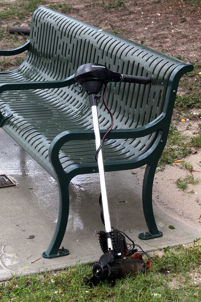 A boat motor leans against a bench at Island Park.