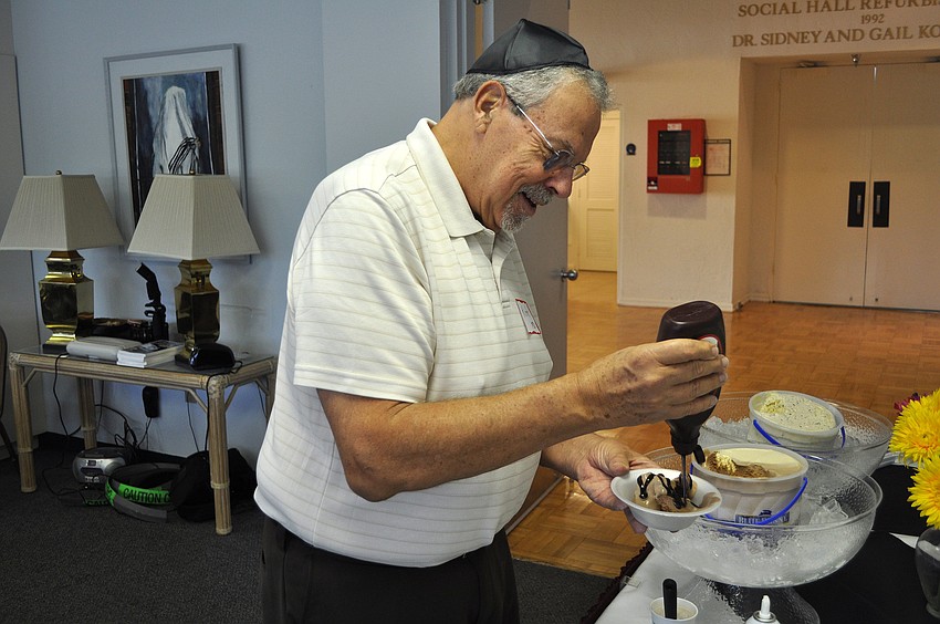 Kirk Donovan puts some chocolate sauce on his sundae, Sunday, Aug. 5, at Temple Beth Sholom.