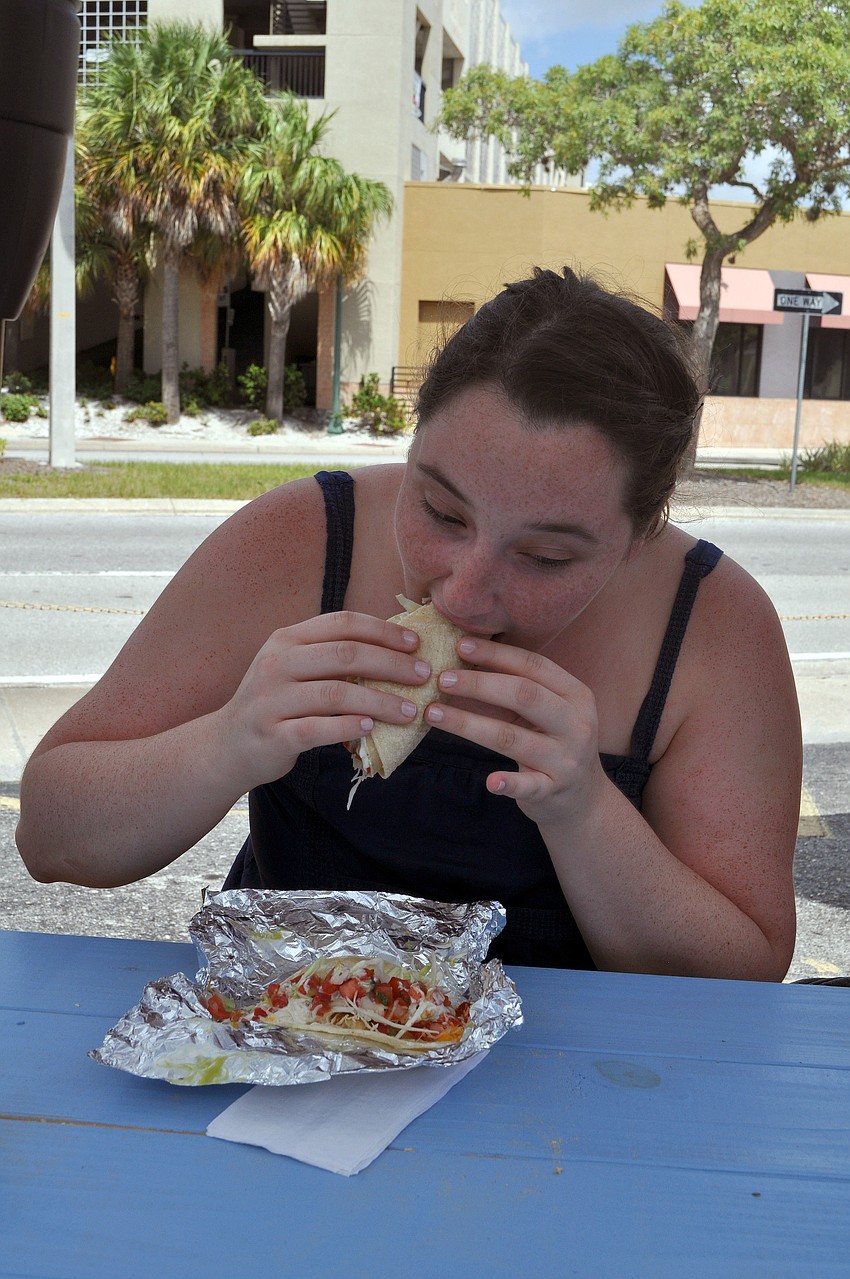 Emily Zier takes a bite out of one of her two battered fish tacos with everything.