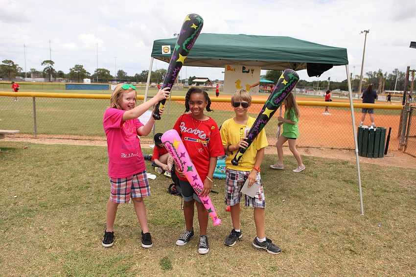 Jennifer Williams, 11, Myah Scott, 10, and Walter Homelster, 11, pose with the inflatable baseball bats they won by playing games, Friday, May 4, out at Twin Lakes.