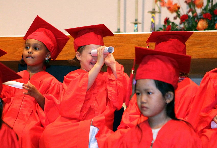 A young graduate looks through her diploma like a telescope during the graduation ceremony, Friday, June 1, at St. Boniface.