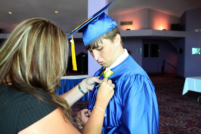 Lori Moyer helps A.J. Johnson get his yellow rose pinned onto his gown, Sunday, June 3.