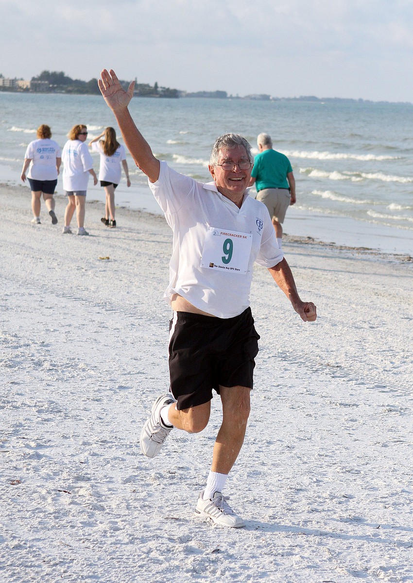 Vern Johnson waves as he heads towards the finish line.