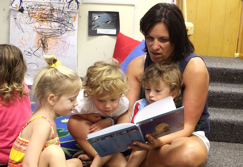 Susan Carney reads a book about penguins to Madeleine Conger, Brooks Becker and Phillip Streckert.