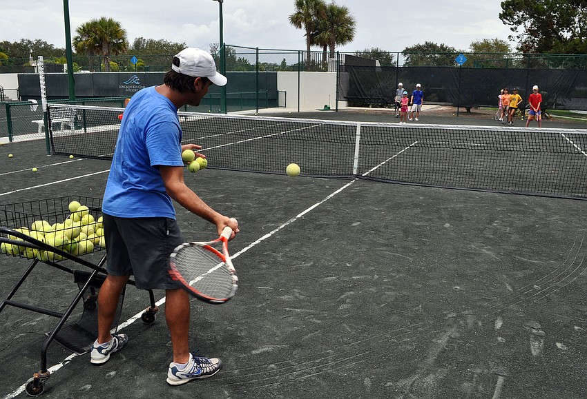 Coach Todd Scheck feeds balls to the tennis camp kids, Monday, July 23, at Longboat Key Club Tennis Gardens.