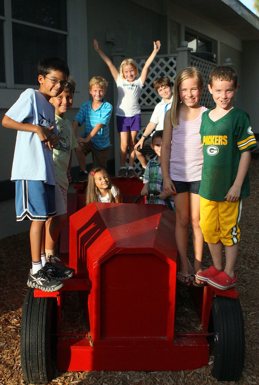 Students piled onto the red, wooden car on the playground at ODA.