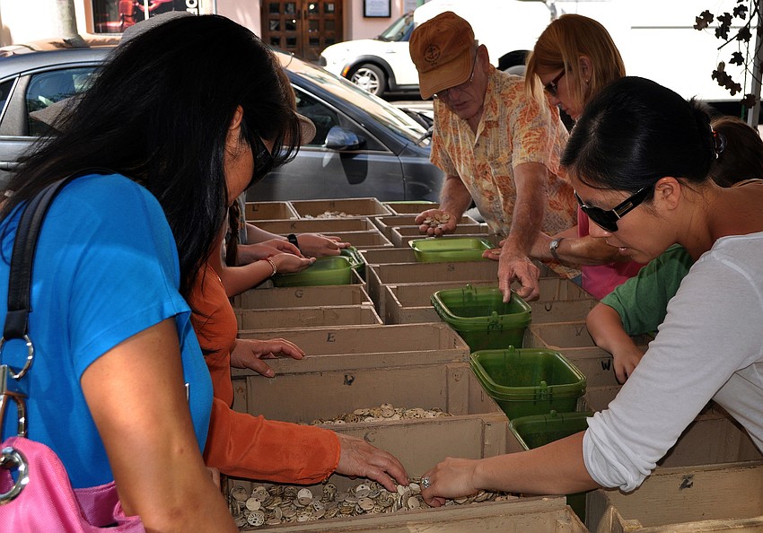 People look through the boxes of ceramic name medallions made by local company, Lora Thomas Ceramics.