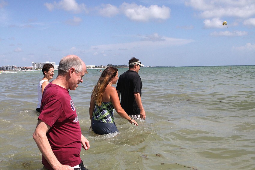 Pastor Craig King leads Leslie Ambrosio, John Hamel and Jenny Glassmoyer into the Gulf of Mexico for their baptisms, Sunday, July 31, out on Siesta Key.