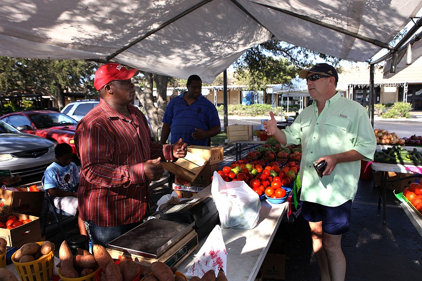 Vincent Morrow sells produce to Steve Sadoskas Sunday, Sept. 1 at the Siesta Key Farmers Market.