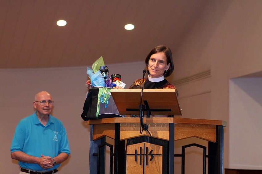 Rev. Andi Taylor presents Dick Aubry with a tennis gift basket as a retirement and thank you gift during graduation.
