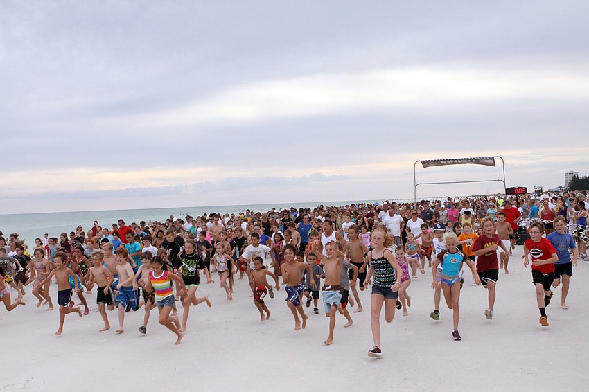 Kids and parents bolt from the starting line, Tuesday, June 19, during the second week of the Summer Fun Run on Siesta Key Public Beach.