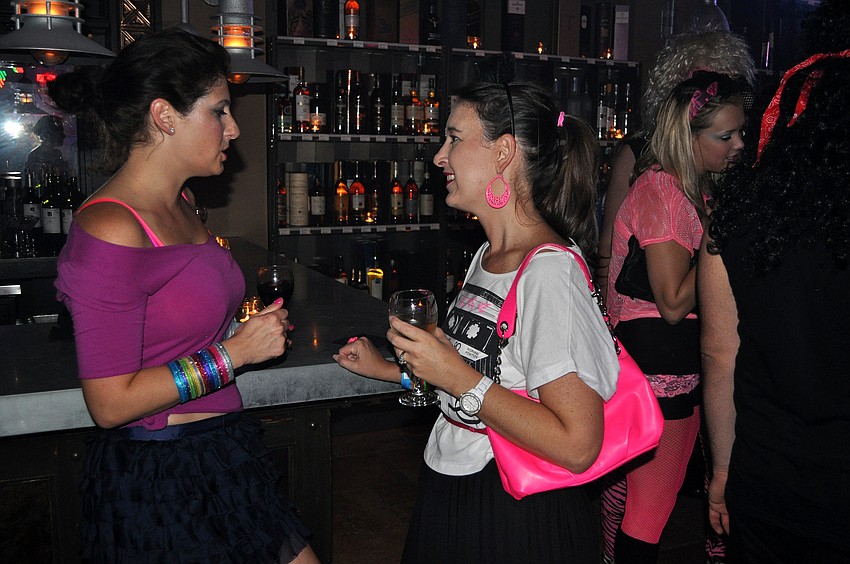 Rian Jones and Jenny Compton talk with one another at the bar.