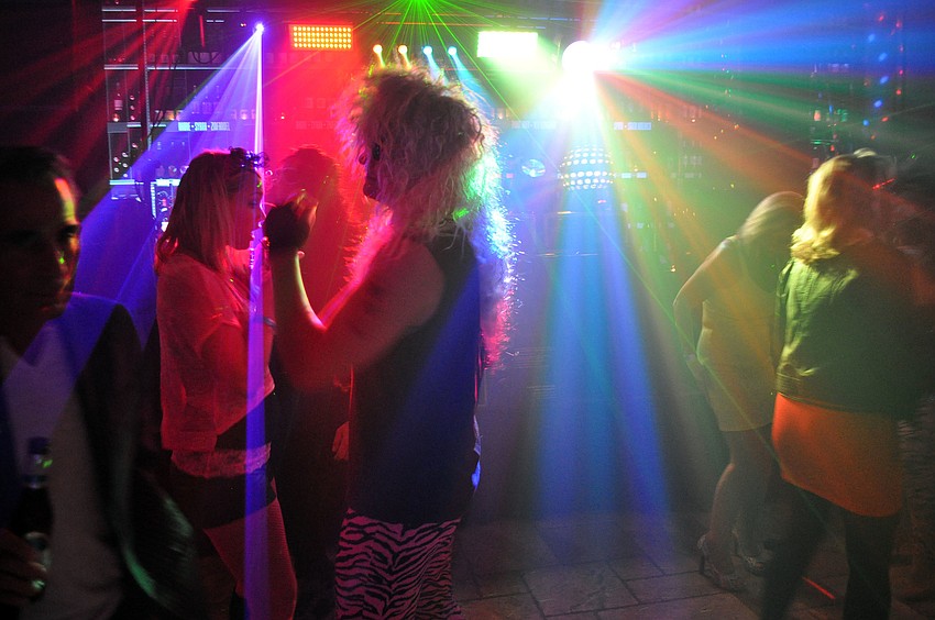 People rock out in their best 80â€™s rocker clothes to a DJ inside Michaelâ€™s Wine Cellar.