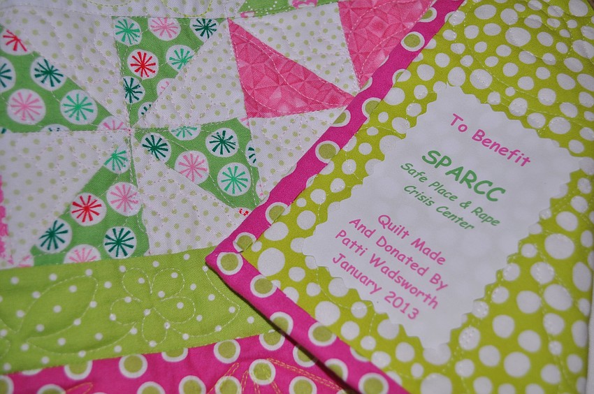 The quilt on the silent auction table has a tag sewn in that says that it was made by Patti Wadsworth to benefit SPARCC.