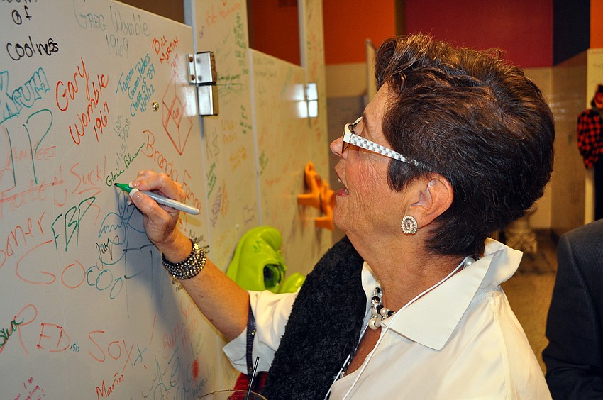 Gloria Biberman writes her name and her husbandâ€™s name on one of the stall doors in the bathroom.