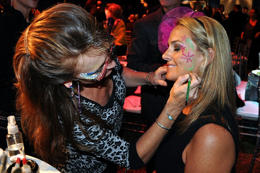 Amy Keiser paints Katie Cassaniâ€™s face with flowers.