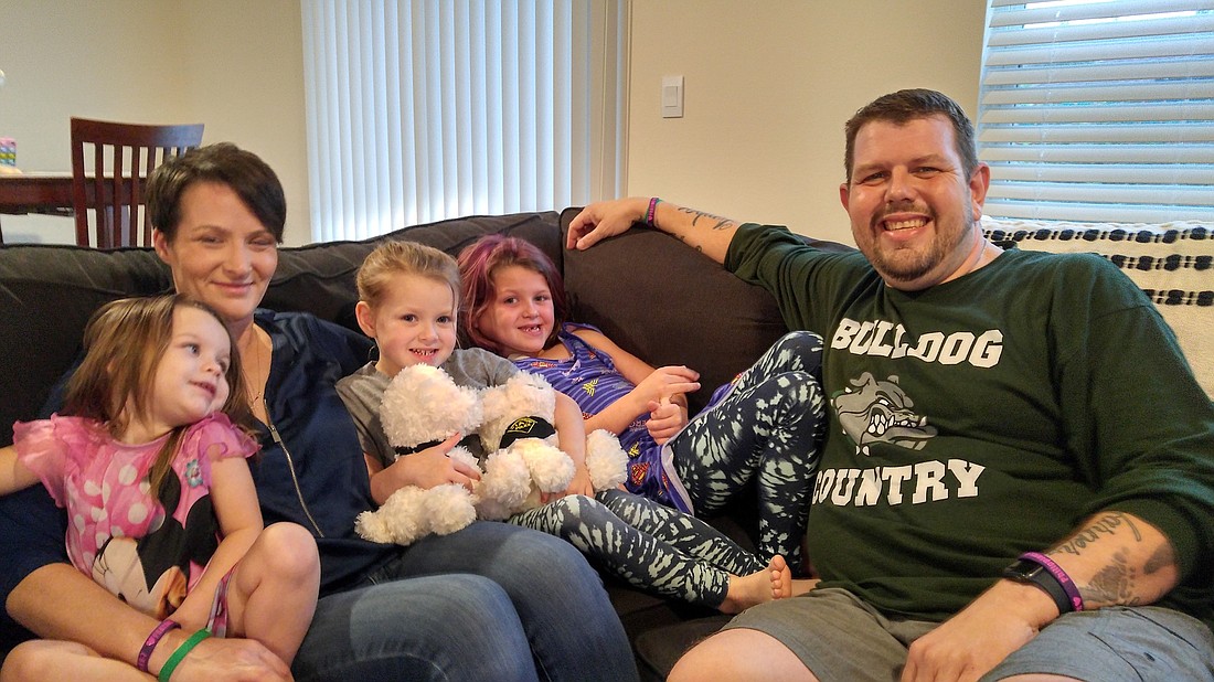 Hudson, 2, Amber, Holland, 4, Harper, 6, and Anthony Wagner sit in their living room. Photo by Brent Woronoff