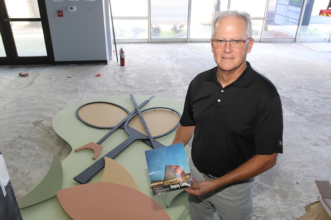 City Commissioner Dwight Selby holds an old publication featuring the Ellinor Village Shopping Center. Photo by Jarleene Almenas