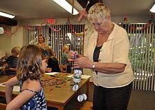 Lynda Fischer, ChapelKidz teacher, helps Chloe Johnson, 7, with her Moses mobile Sunday, Sept. 23, during the ChapelKidz open house at Siesta Key Chapel.