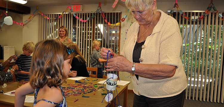 Lynda Fischer, ChapelKidz teacher, helps Chloe Johnson, 7, with her Moses mobile Sunday, Sept. 23, during the ChapelKidz open house at Siesta Key Chapel.