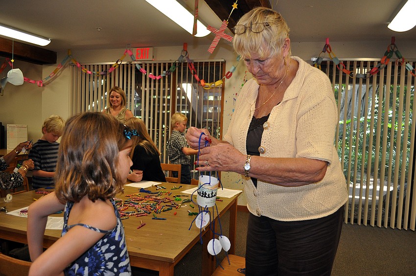 Lynda Fischer, ChapelKidz teacher, helps Chloe Johnson, 7, with her Moses mobile Sunday, Sept. 23, during the ChapelKidz open house at Siesta Key Chapel.
