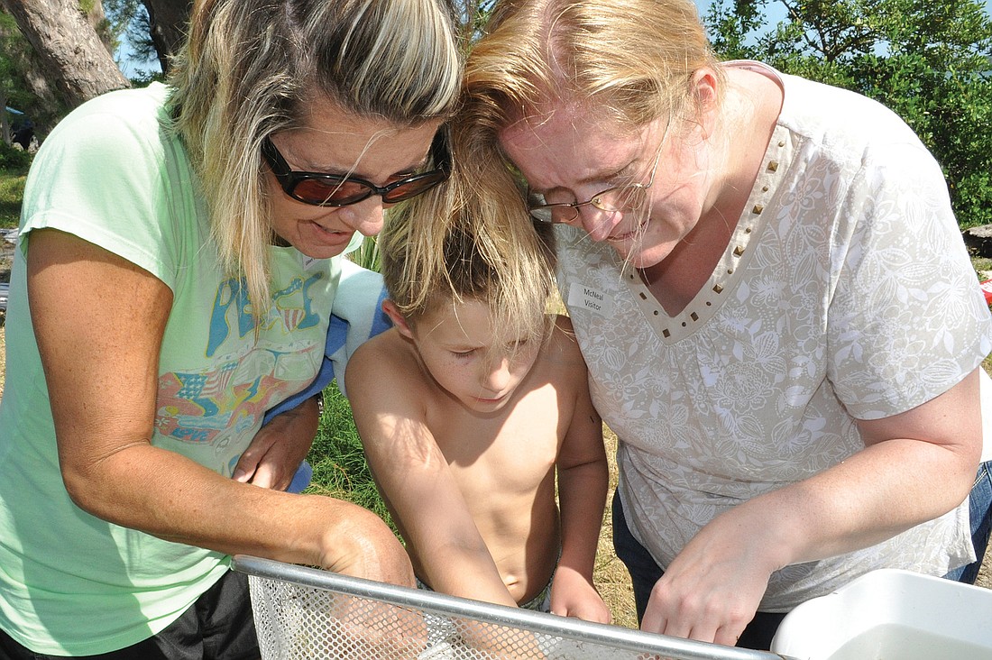 Parent volunteers Amy Goodman and Denise Radenmacher help student Micah Radenmacher, center, get all the sea creatures from his net.