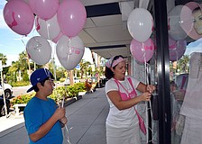 Michael Hampton, 11, helps his mom, Joanne, tie breast cancer awareness balloons onto the handles of stores that participated in the Circle Me Pink event Saturday, Oct. 6, on St. Armands Circle.