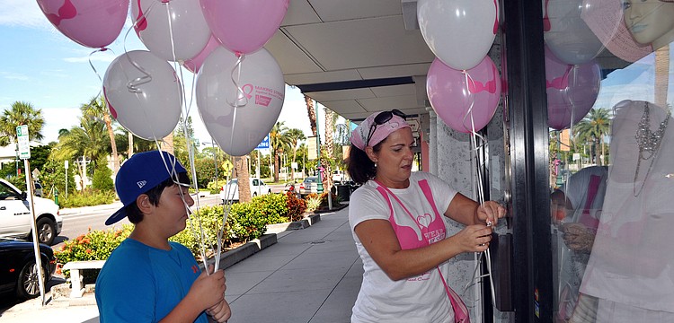 Michael Hampton, 11, helps his mom, Joanne, tie breast cancer awareness balloons onto the handles of stores that participated in the Circle Me Pink event Saturday, Oct. 6, on St. Armands Circle.