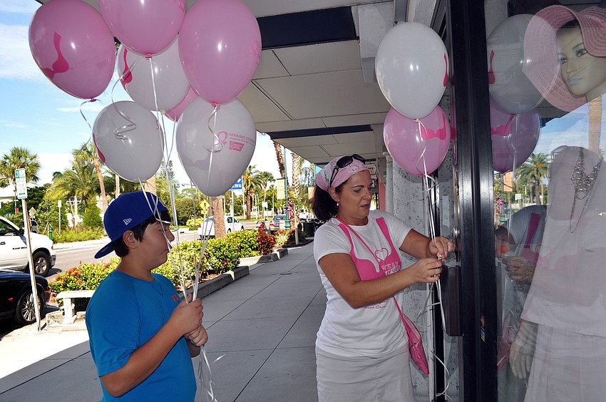 Michael Hampton, 11, helps his mom, Joanne, tie breast cancer awareness balloons onto the handles of stores that participated in the Circle Me Pink event Saturday, Oct. 6, on St. Armands Circle.