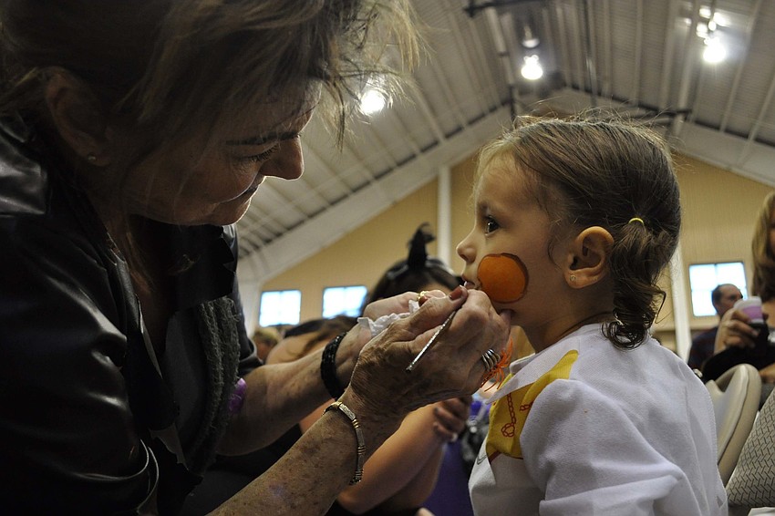 Marge Wallick put the finishing touches on the face of Aleigha Quiroz, 2.
