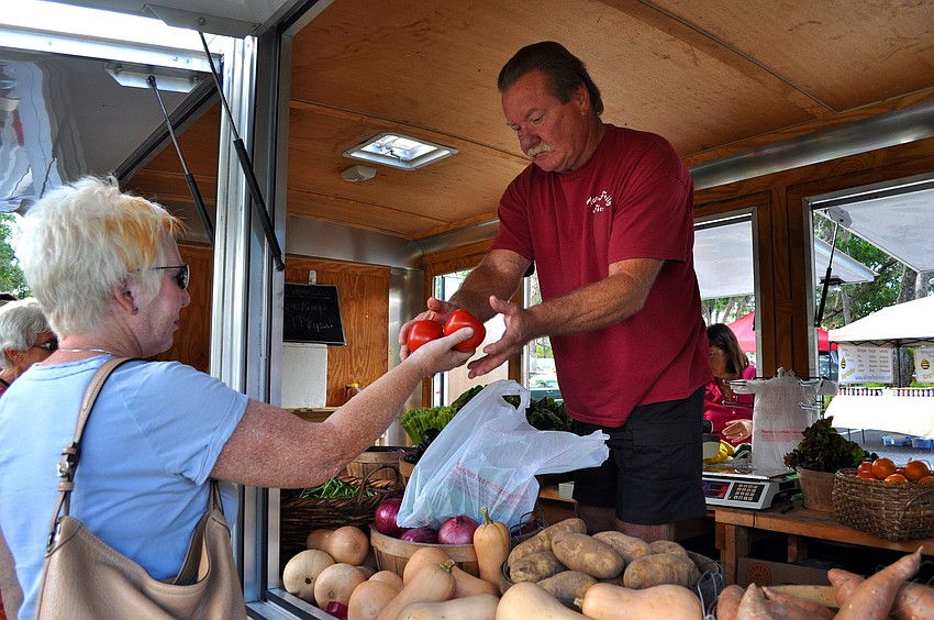 Julie Bales buys some green beans and tomatoes from Randy True from the True Family Farm trailer Sunday, Oct. 28, during the Fall Festival at the Centre Shops.
