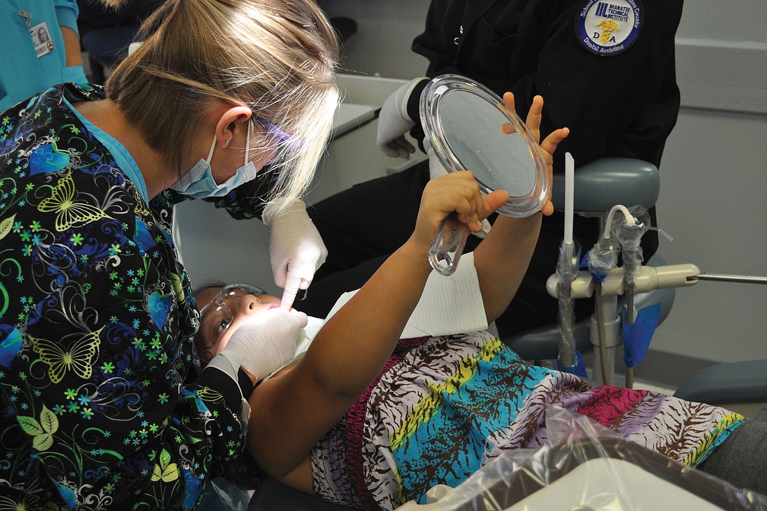 Kimberly Garcia watched as an MTI dental assistant teaches the 7-year-old how to floss.