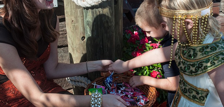 Alexandra Scott hands out candy to siblings Sean and Jenavieve McDonnell in front of The Cottage.