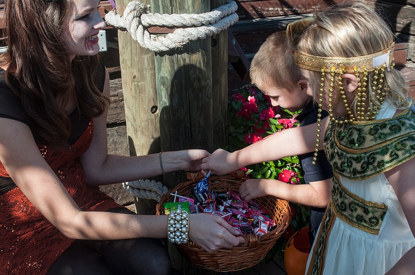 Alexandra Scott hands out candy to siblings Sean and Jenavieve McDonnell in front of The Cottage.