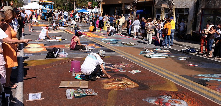 Chalk artists work on their pieces Saturday, Nov. 3, as spectators walk by and watch them work.