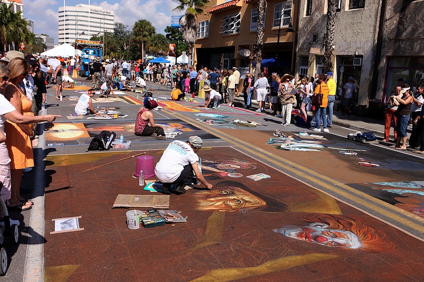 Chalk artists work on their pieces Saturday, Nov. 3, as spectators walk by and watch them work.