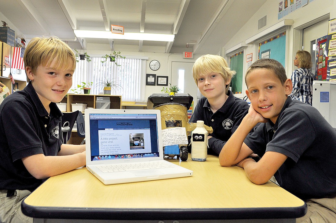 Evan Lagassee, William Lahners and Charlie Kempston show off their website and their robot, ROB. E.