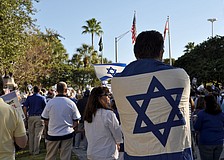 A man drapes the flag of Israel over his back in a show of support.