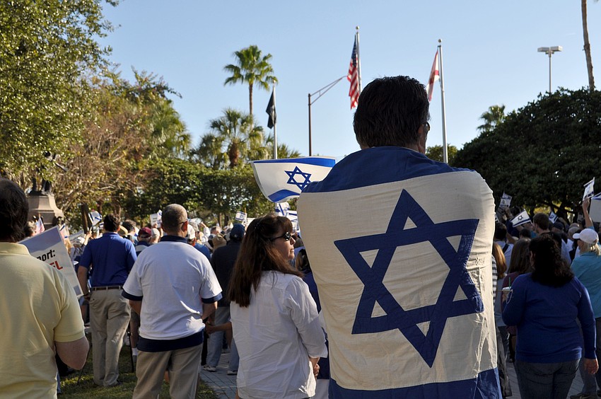 A man drapes the flag of Israel over his back in a show of support.