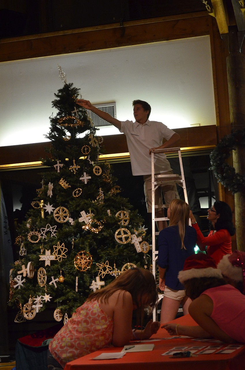 Alex Mooney puts the finishing ornaments on the Christmas tree at Siesta Chapel on Sunday, Dec. 2.