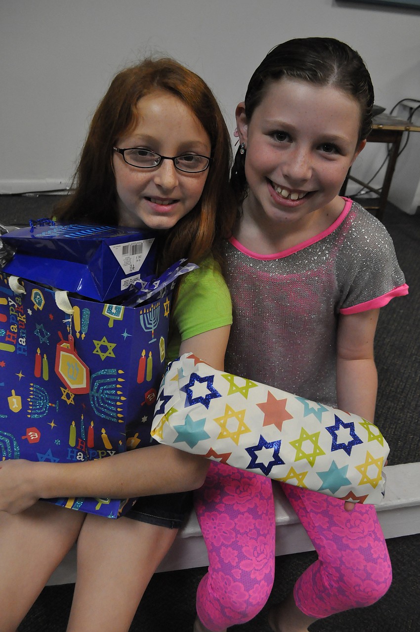 Rebecca Kelinberg, 10, and Emma Katz, 11, hold Hanukah gifts.