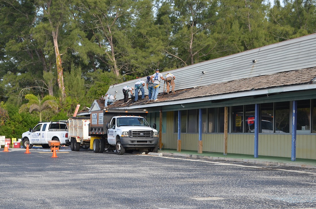A construction crew began tearing off the old roof on Whitney Beach Plaza on Monday.