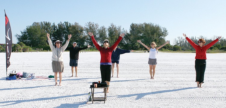 Kathy Oravec leads the group in reaching up high during the beginning of her NIA class, April 24, on Siesta Key Public Beach.