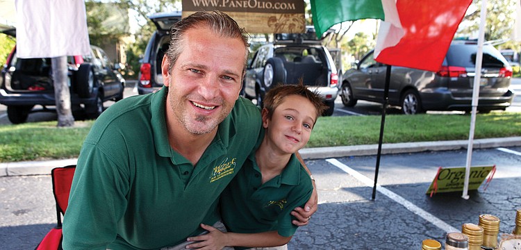 Pino Mazzone with his son, Riccardo, 8, have fun together selling Paneolio olive oil, Sept. 2, at the Siesta Key Farmers Market. Paneolio has had a booth at the farmers market for years, and Mazzone brings his son along to help out many Sundays.