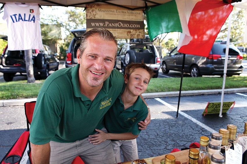 Pino Mazzone with his son, Riccardo, 8, have fun together selling Paneolio olive oil, Sept. 2, at the Siesta Key Farmers Market. Paneolio has had a booth at the farmers market for years, and Mazzone brings his son along to help out many Sundays.