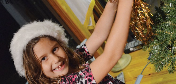 Chloe Johnson decorates the Siesta Key Chapel Christmas tree Sunday, Dec. 2, after the church's Advent dinner.